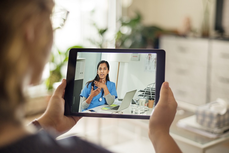 Woman holding a tablet and speaking to doctor on virtual call