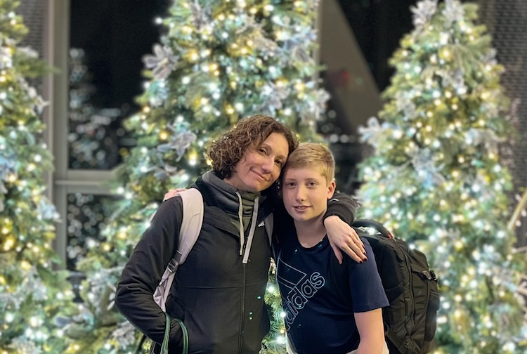 Dani and her son standing in front of lit christmas trees