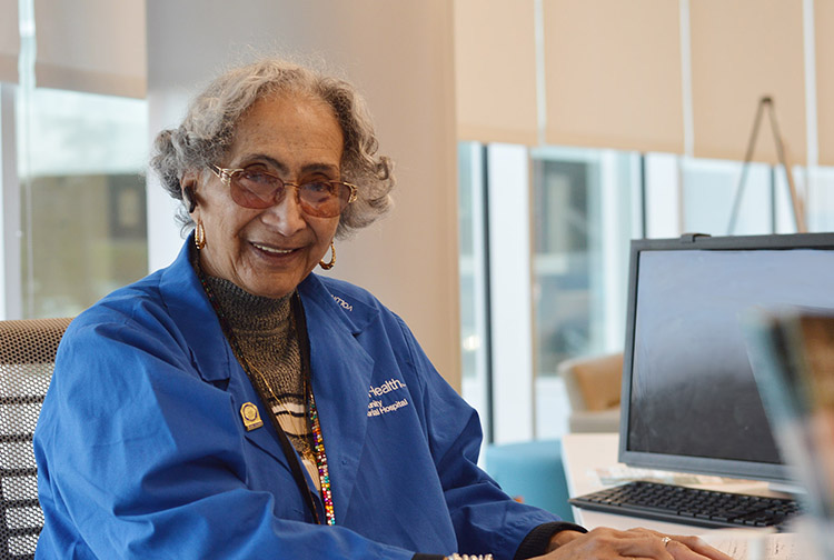 A volunteer wearing a blue jacket sits at a computer.