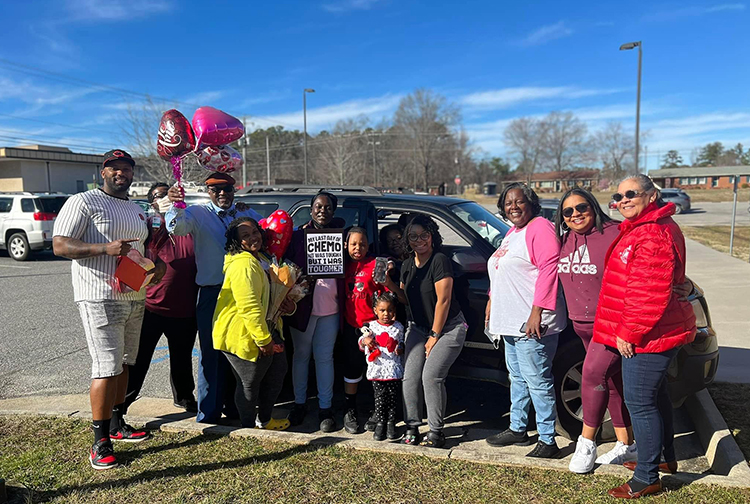 A large family poses with balloons in a parking lot