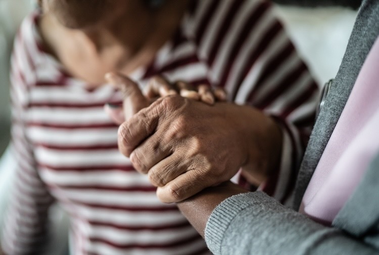 home caregiver and senior woman holding hands at home