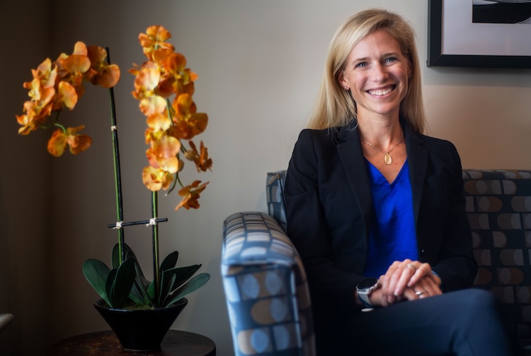 Dr. Breton sits on a couch with a yellow orchid to her left
