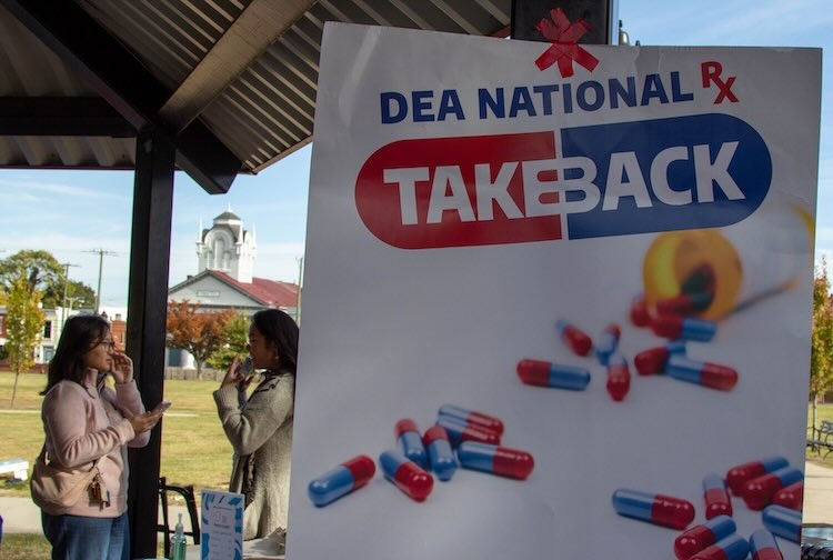 Students talking behind a sign for Drug Take Back Day.