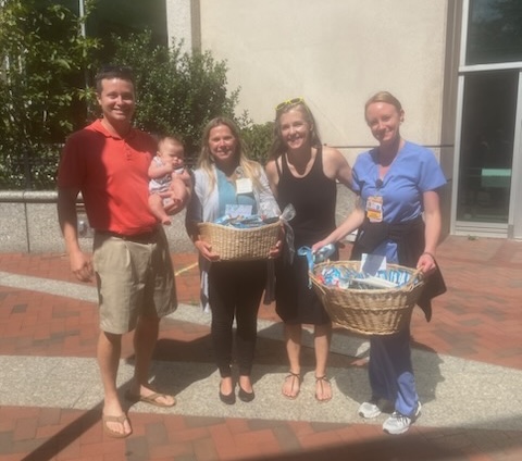 Four people standing outside hospital with baskets of snacks.