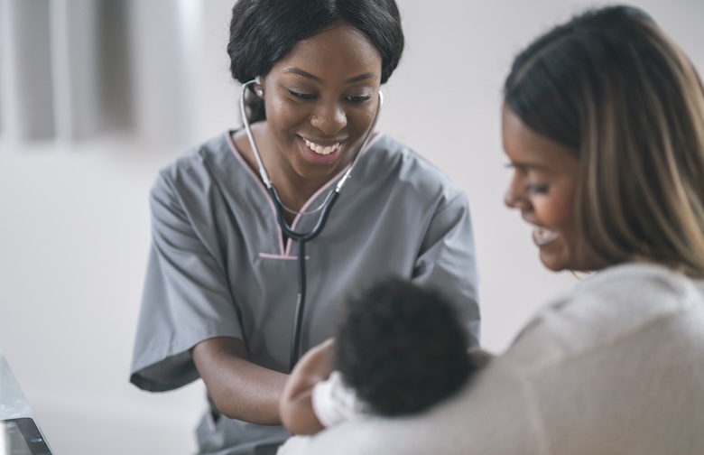 health care provider speaking with mom and looking at her baby.