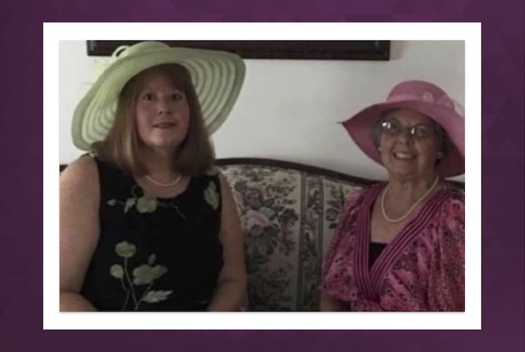Two women in big, fancy hats sitting next to each other