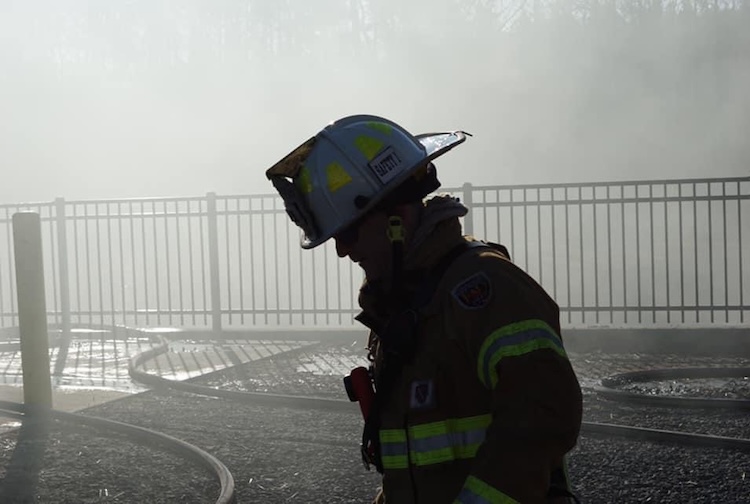 Greg Leitz stands in the smoldering smoke after fighting a fire.