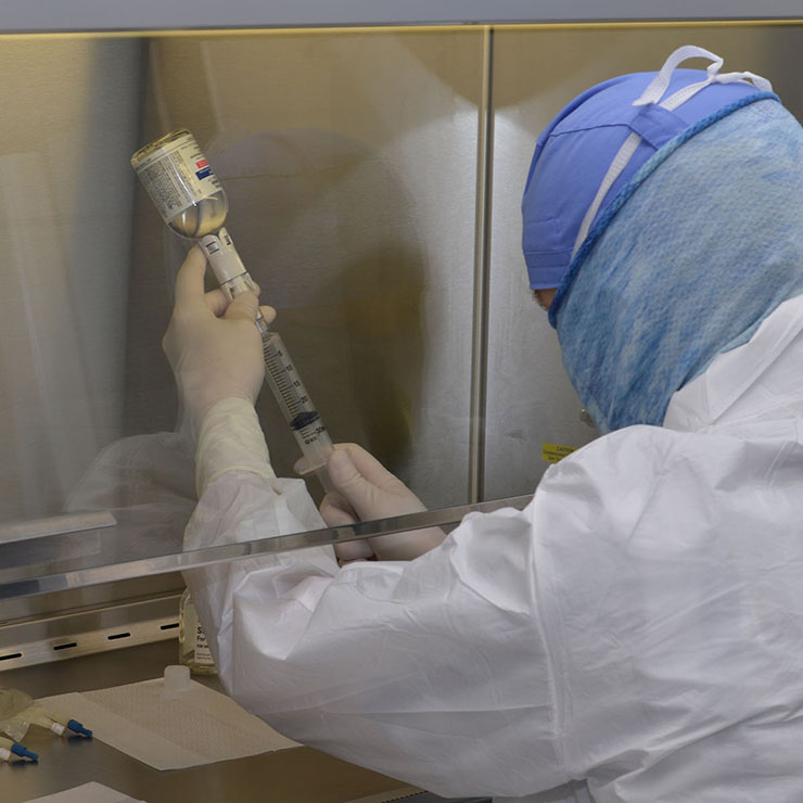 Ray Hayes, CPhT, mixes medication into IV bags in the clean room hood. Mr. Hayes has worked at VCU Health CMH for seven years and resides in Boydton.