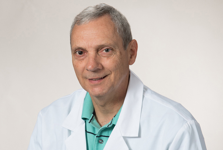 A physician in a white lab coat and turquoise polo.