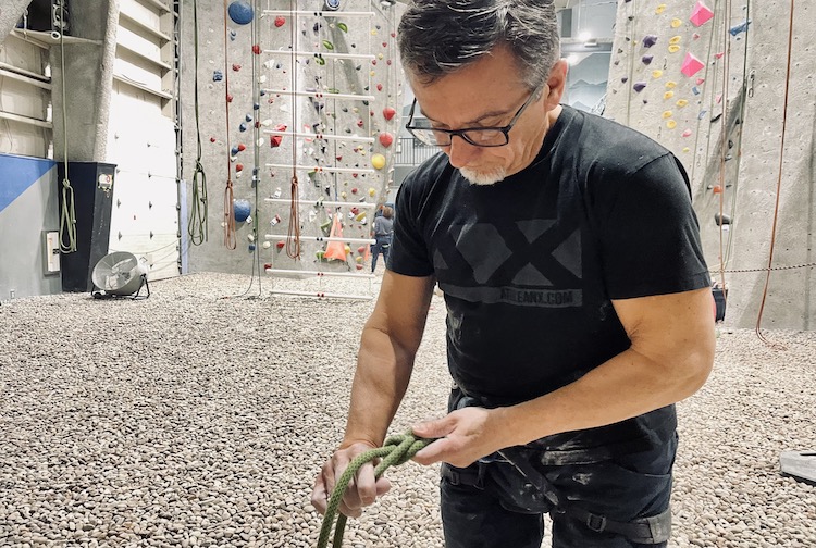 Man wipes chaulk on his hands as he prepares to go up a rock climbing wall.