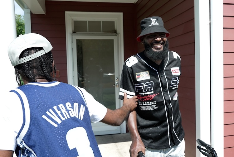 Man standing with walker on porch with a friend