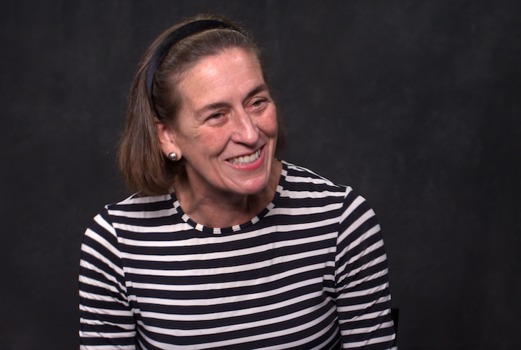 Woman in a striped black and white shirt smiles.