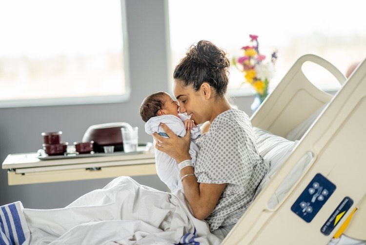 Mother rubbing noses with newborn in hospital bed