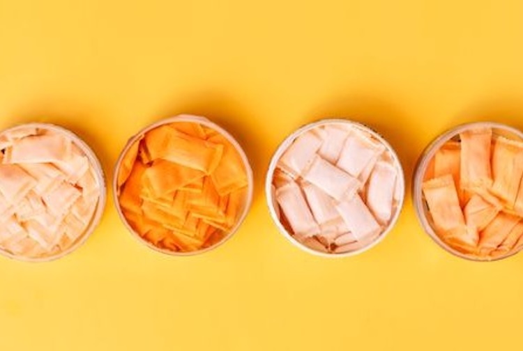 Tins with nicotine pouches that are peach and orange