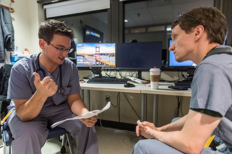 two people talking in scrubs in a class room