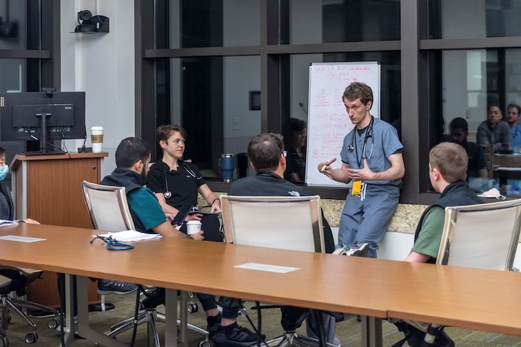 classroom lecture with people talking in scrubs worn by medical staff.