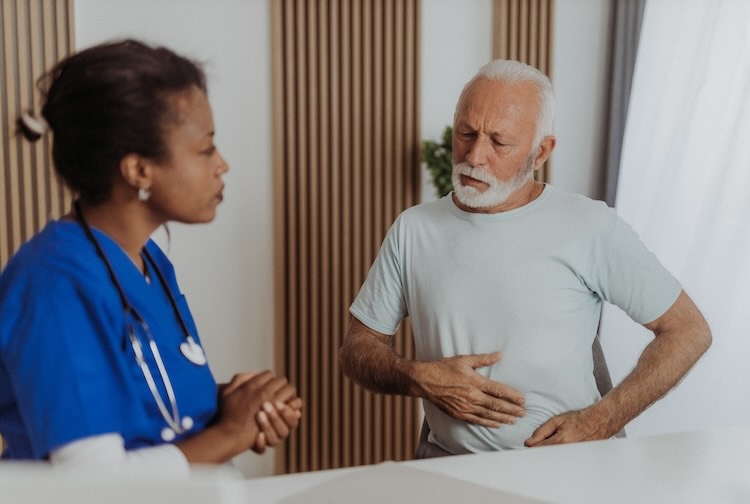 Older man visits doctor because of stomach pain from a gastrointestinal illness.
