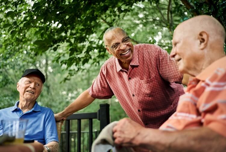 Group of happy older man gathered around a table.