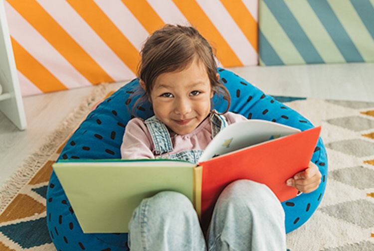 Child sitting on bean bag with a book open