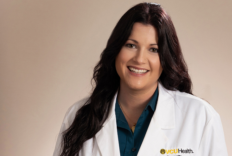 A smiling brunette wearing a white lab coat