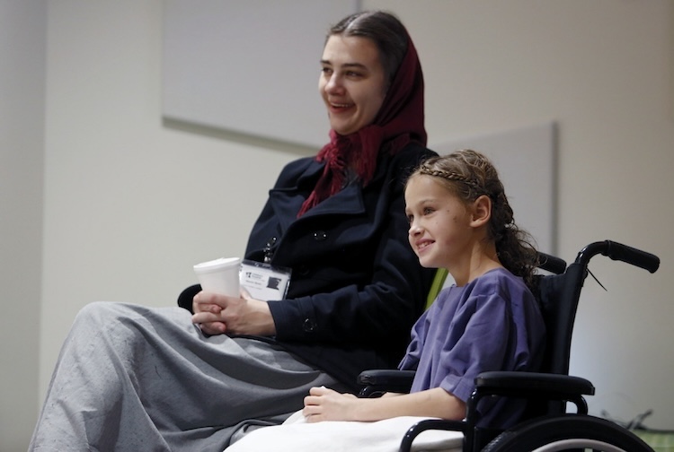 Little girl in a wheel chair and her caretaker smiling