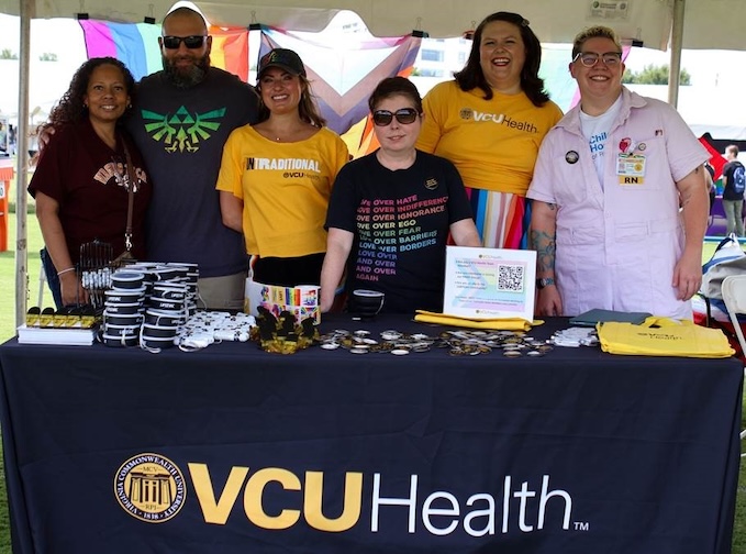 Group standing behind a table handing out VCU Health swag at a festival