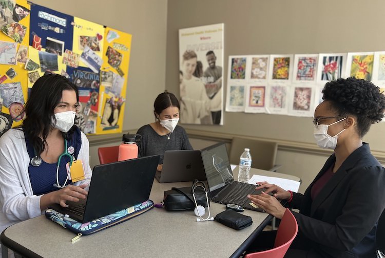 Three female students sit around a table working. They are part of the Richmond Health and Wellness Program. 