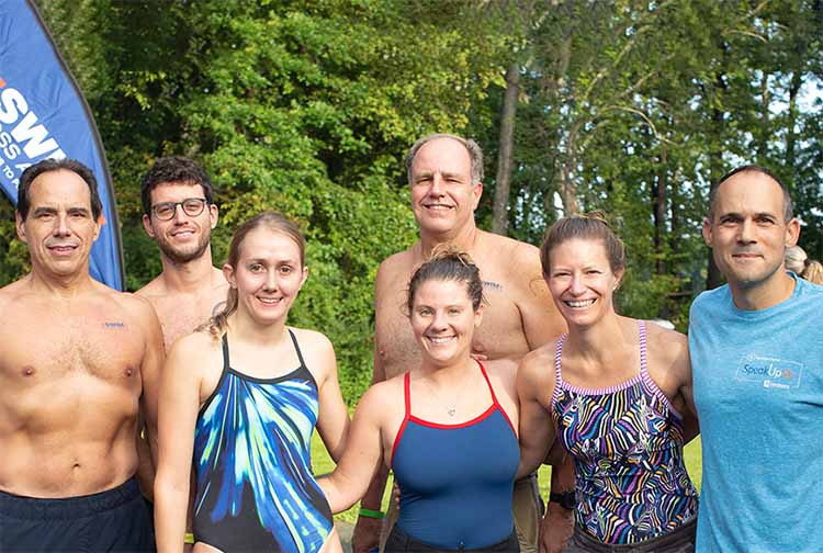 Group stands together in their bathing suits.