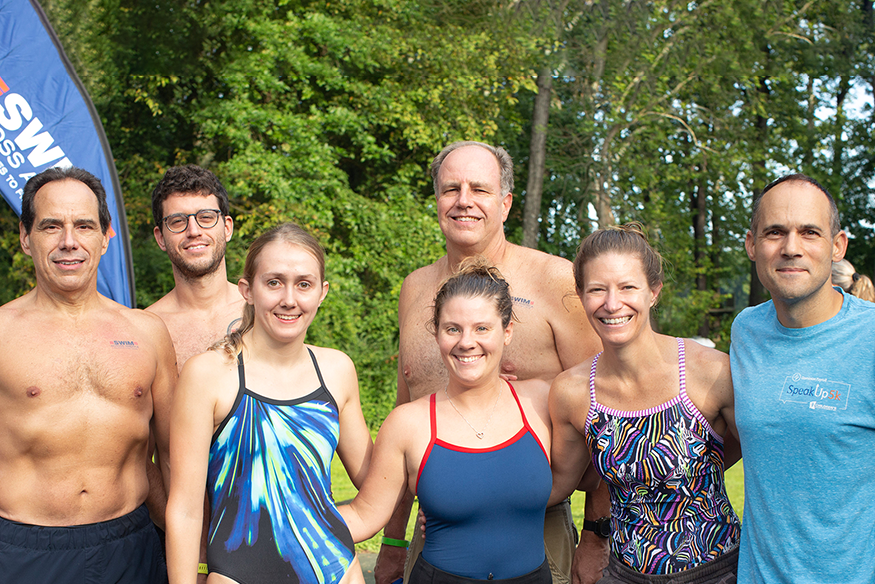Group stands together in their bathing suits.