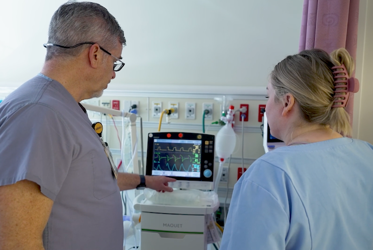 two health care workers look at a monitor tracking a patient's heartbeat 