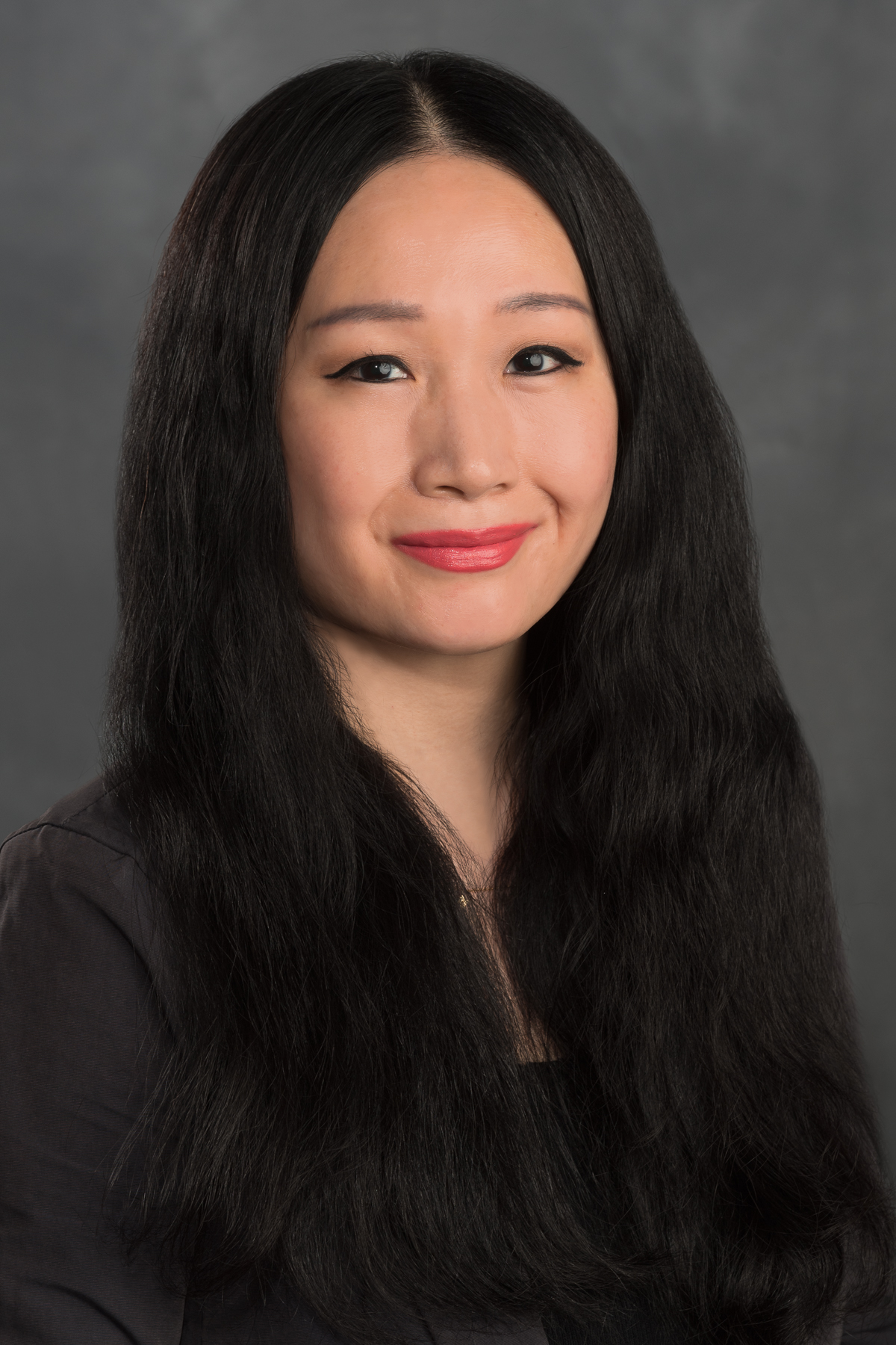 Woman with long black hair and a black blouse.