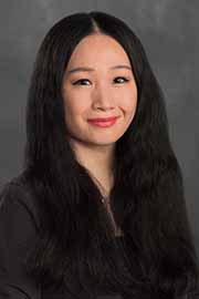 Woman with long black hair and a black blouse.