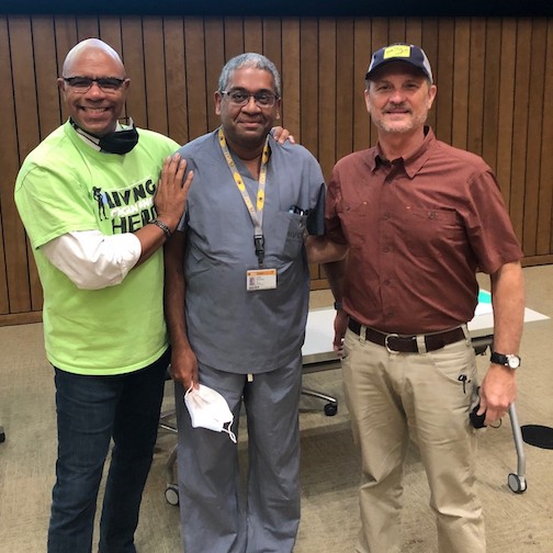 Three men standing together smiling