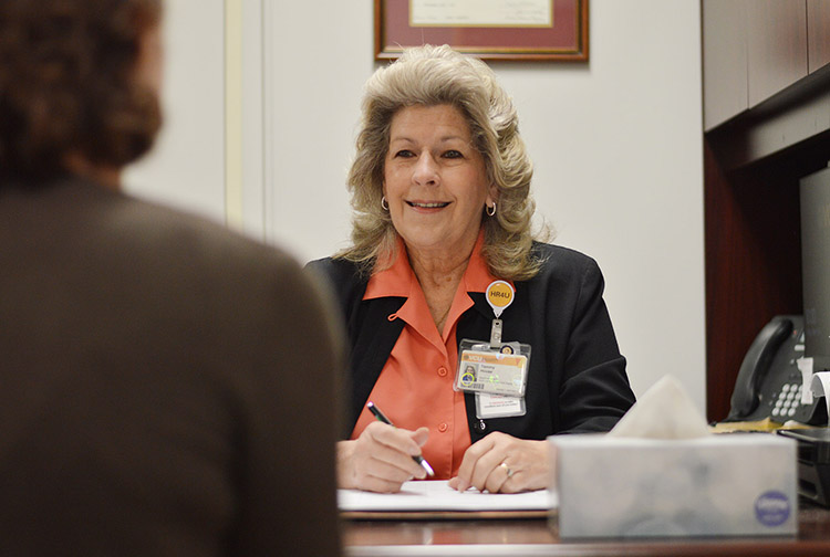 A health care worker at a desk speaks to a patient