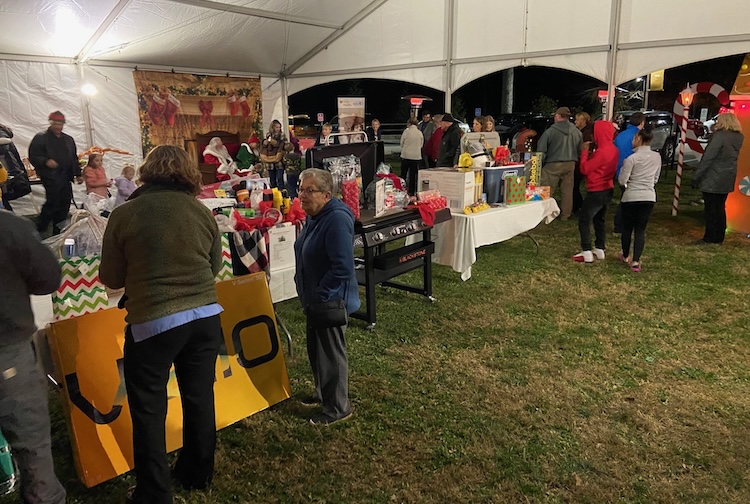 Crowd of people under a tent with raffle prizes.