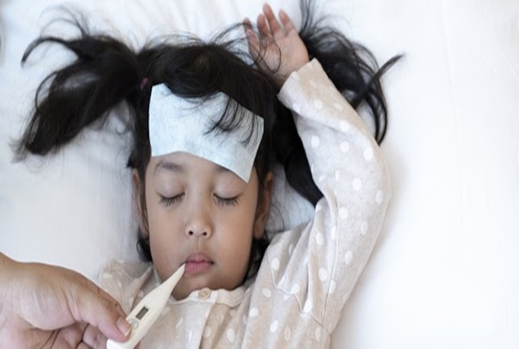Child laying get temperature checked with a thermometer.