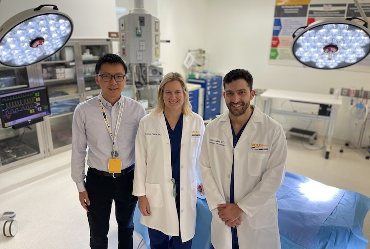 Three people standing in a surgery room