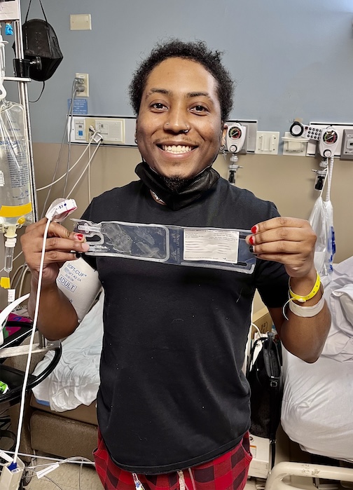 Patient stands holding sign and miles 