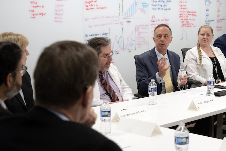 Several people participate in a round table discussion on health sciences and biotech. 