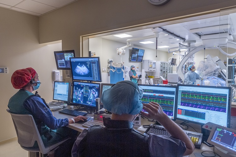Medical team sitting at computers and watching patient undergo medical procedure