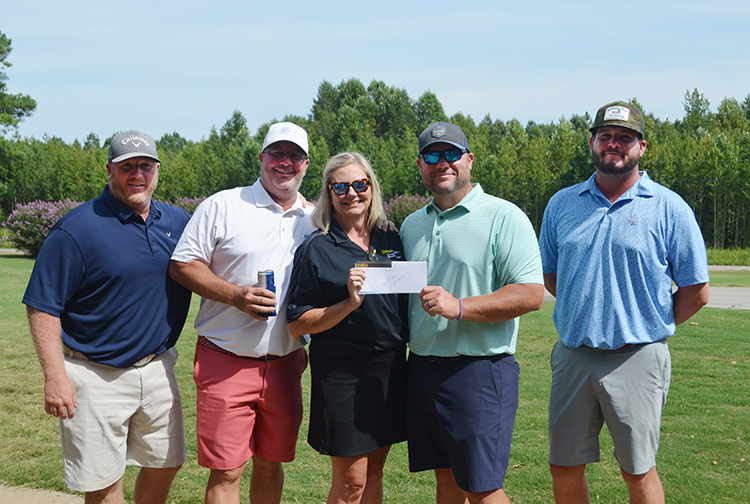 A lady awards four men with a prize on a golf course.