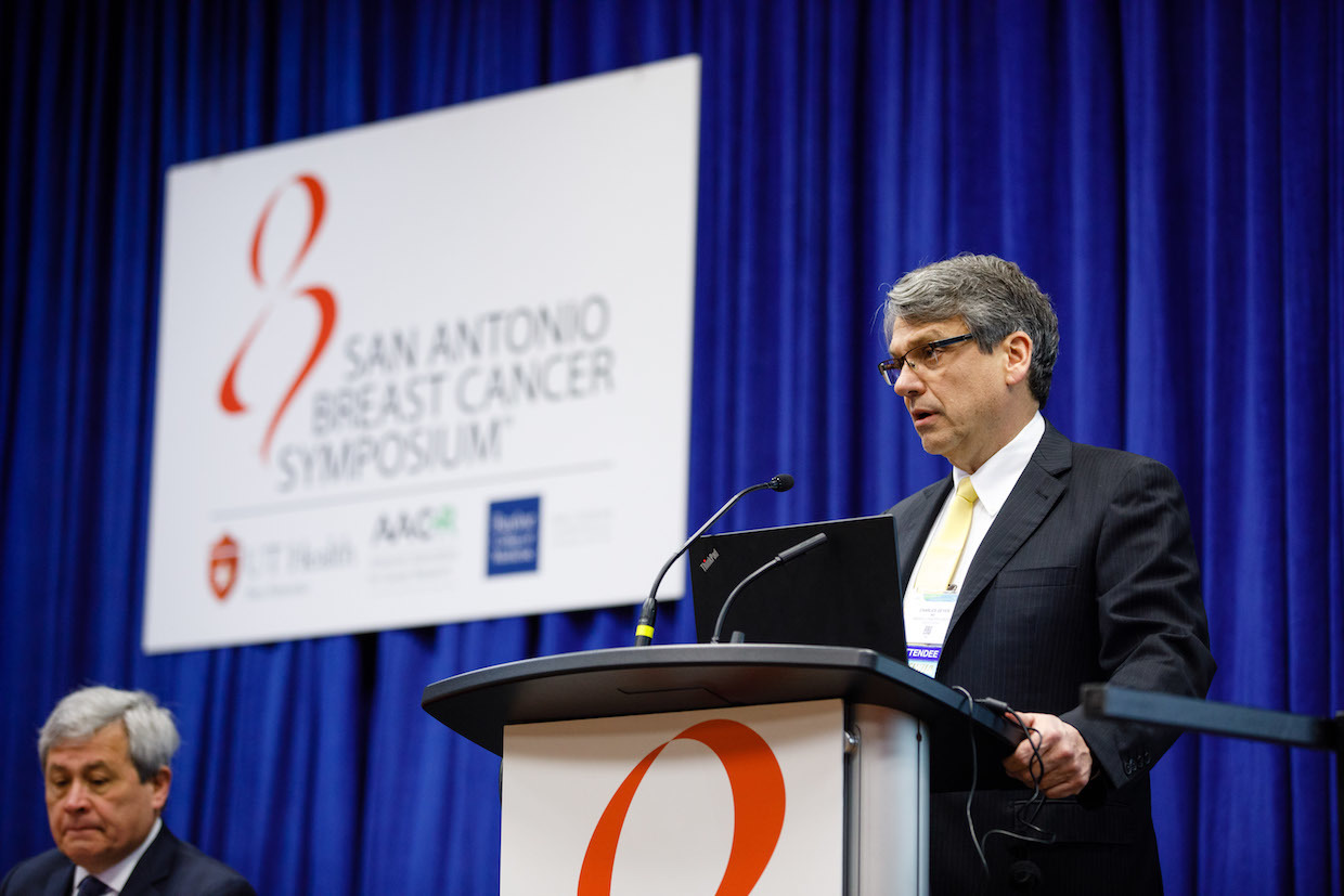 A man in business attire speaks at a lectern.