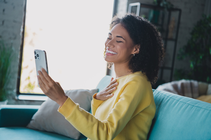 A woman smiles and looks at her phone.