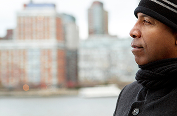 Photograph of a man with buildings in the background.