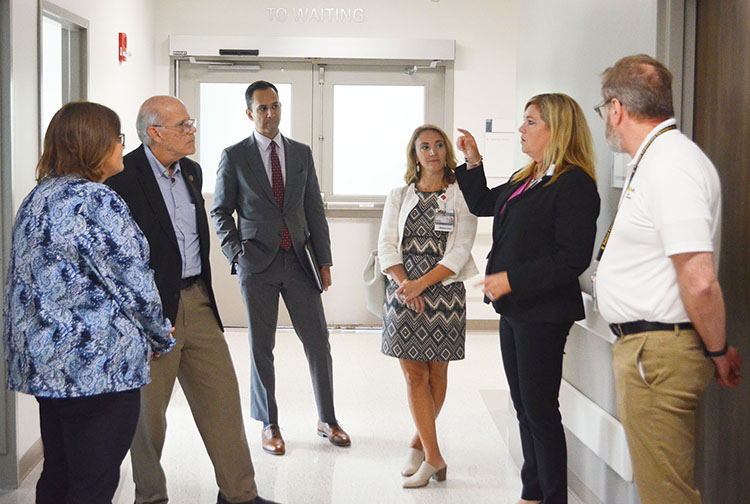 A group of health care workers speak with a visitor in a hospital hallway.