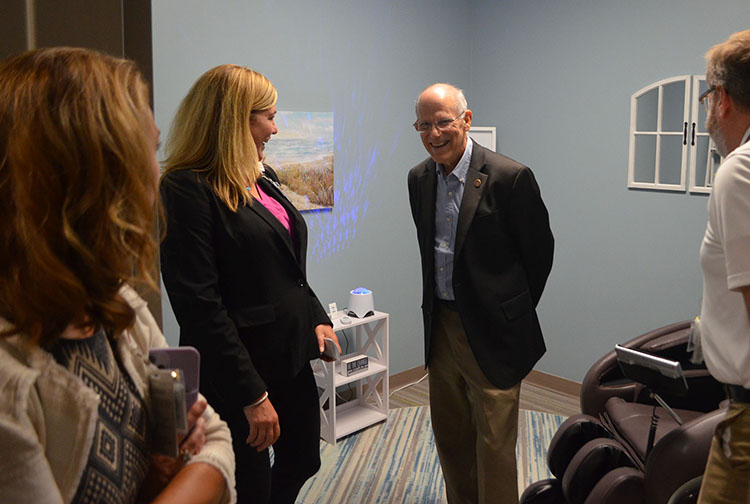 A group of people tour a room with a massage chair.