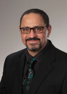 Portrait of Dr. Manhal Saleeby, wearing a black business suit.