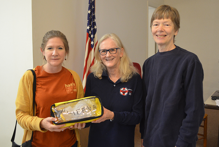 Three people smile for the camera while holding a medical device.