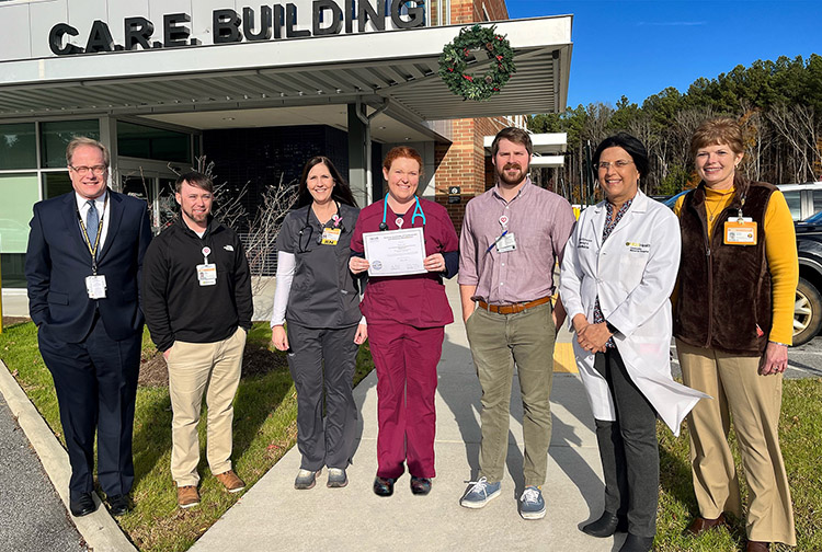 a group of health care workers stand outside the C.A.R.E. Building