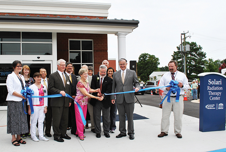 Hospital workers and donors cut the ribbon outside a building.